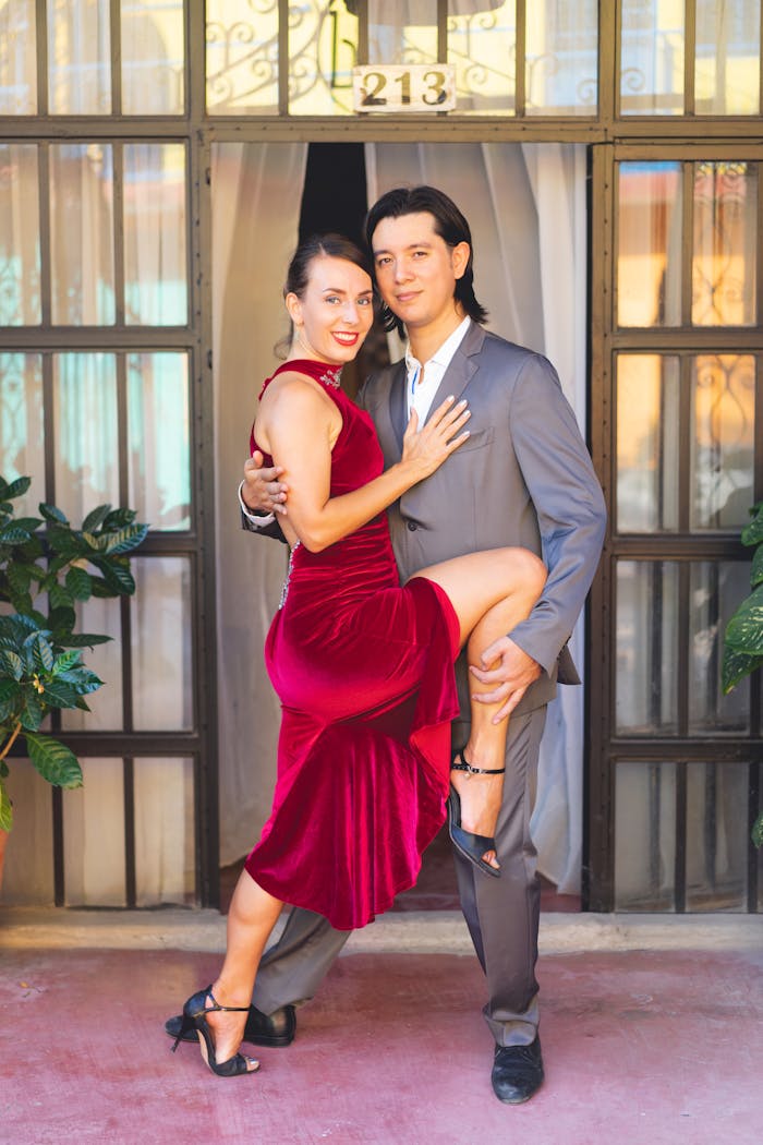 Stylish couple in dance pose, woman in red dress and man in suit, ready for tango.
